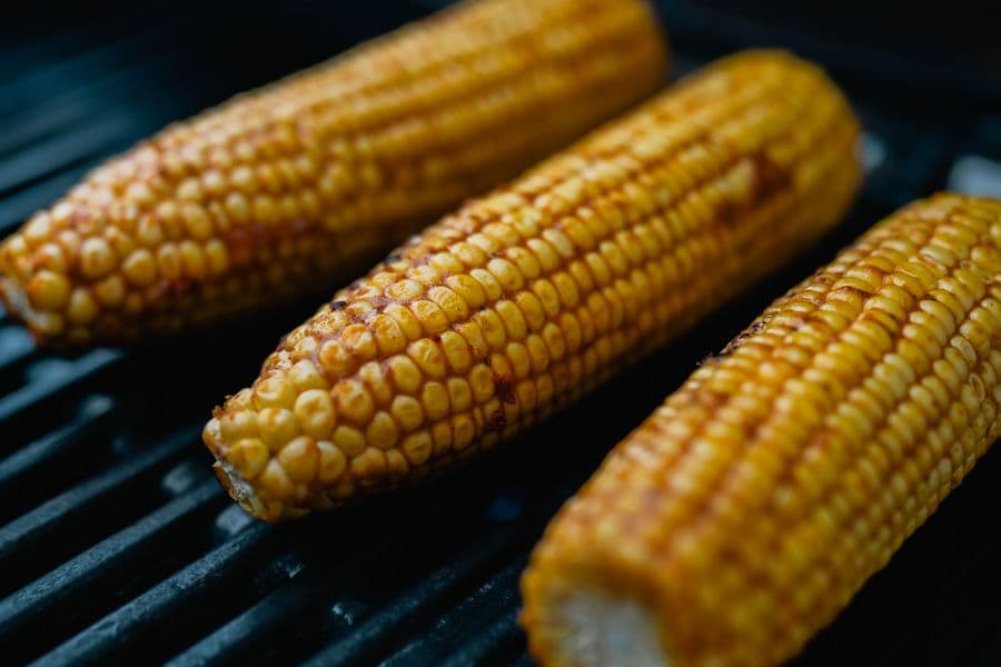 Charred corn on the cob sizzling on a grill