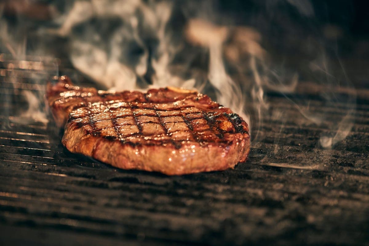 A steak searing over flames on a grill
