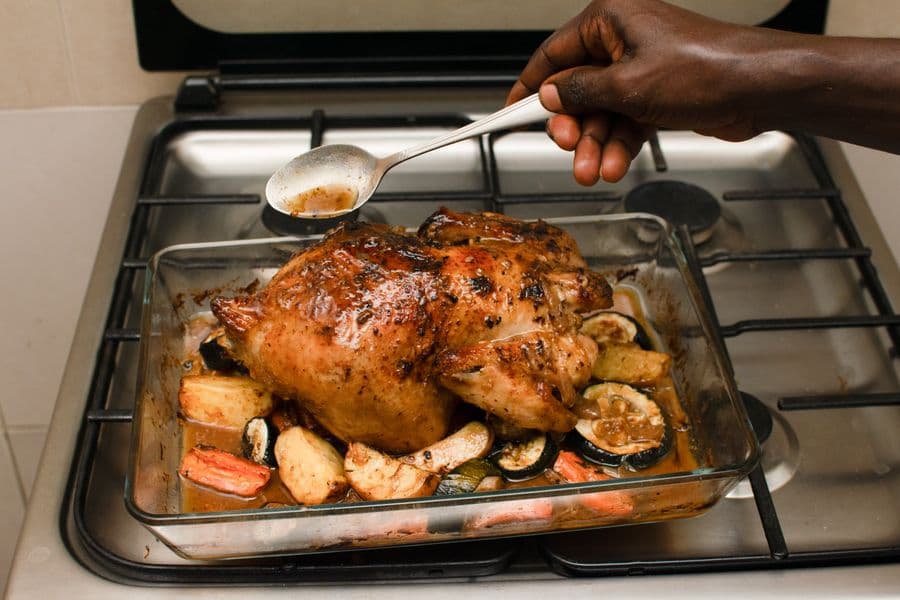 Roast chicken with vegetables being basted