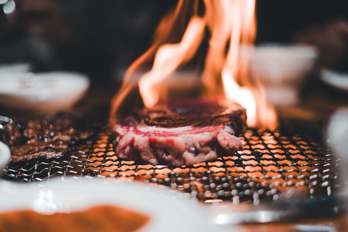 A steak with grill marks cooking over flames