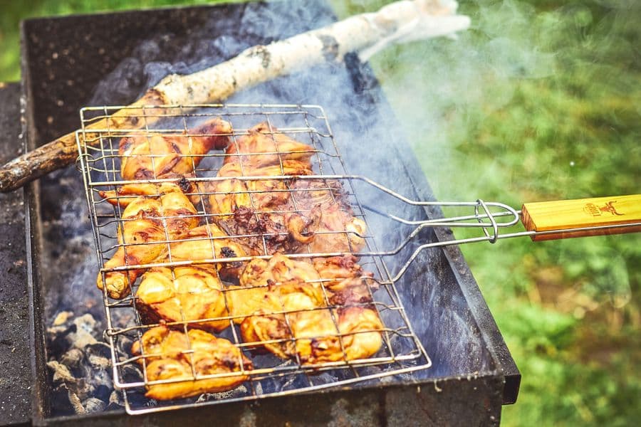 Chicken pieces browning on an outdoor barbecue